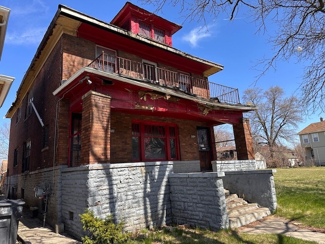 view of front of home with covered porch, brick siding, and a balcony