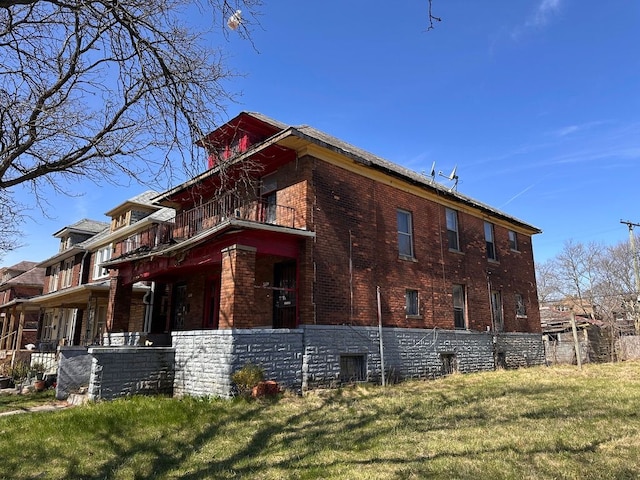 view of home's exterior with brick siding, a yard, and a balcony