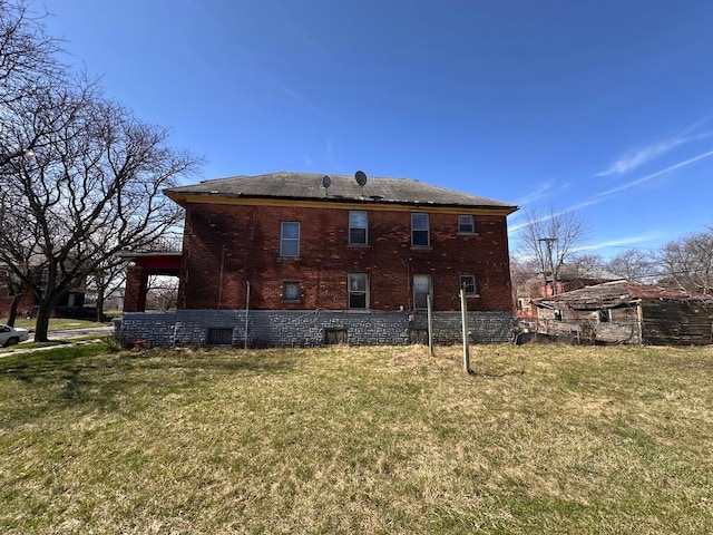 rear view of property featuring a lawn and brick siding