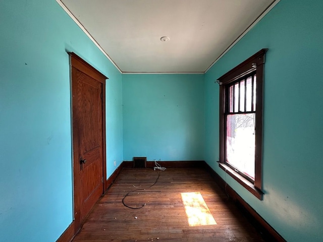 spare room with crown molding, baseboards, and wood finished floors