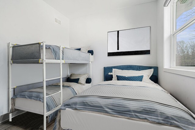 bedroom featuring baseboards, visible vents, multiple windows, and wood finished floors