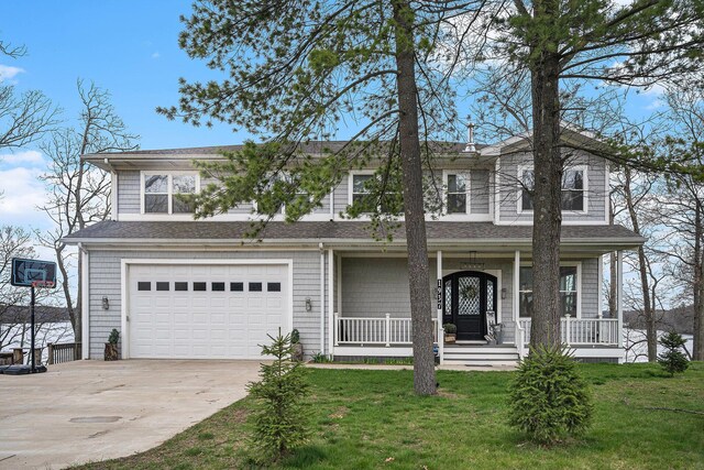 traditional home featuring an attached garage, a front yard, covered porch, and driveway