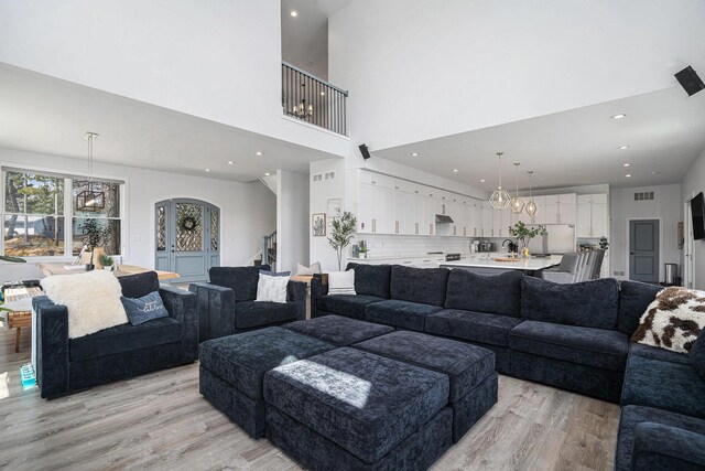 living area with visible vents, stairs, a towering ceiling, recessed lighting, and light wood finished floors