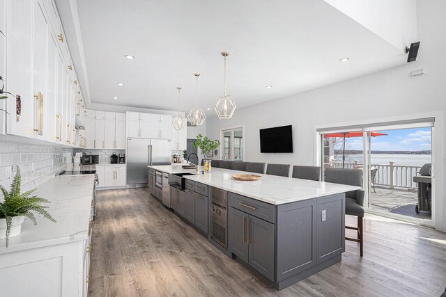 kitchen with a sink, gray cabinets, stainless steel appliances, white cabinetry, and wood finished floors
