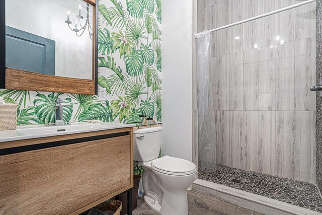 bathroom featuring toilet, a tile shower, and vanity