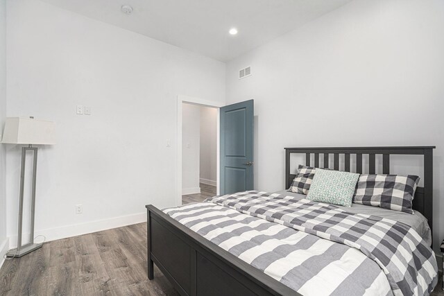 bedroom with a towering ceiling, visible vents, wood finished floors, baseboards, and recessed lighting