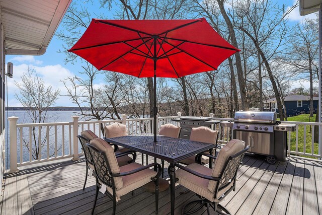 wooden terrace with outdoor dining area, a water view, and grilling area