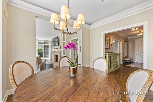 dining area featuring dark wood-style flooring, an inviting chandelier, and a stone fireplace
