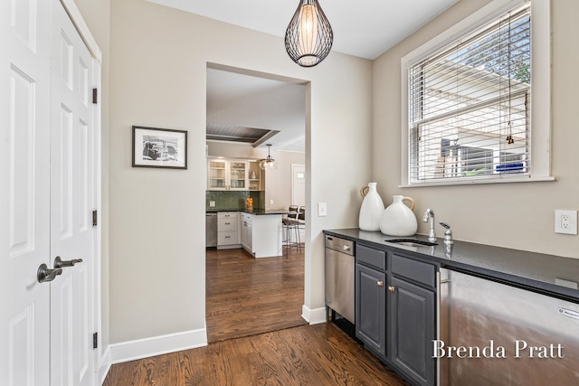 bar with dark wood-style flooring, a sink, baseboards, tasteful backsplash, and stainless steel dishwasher