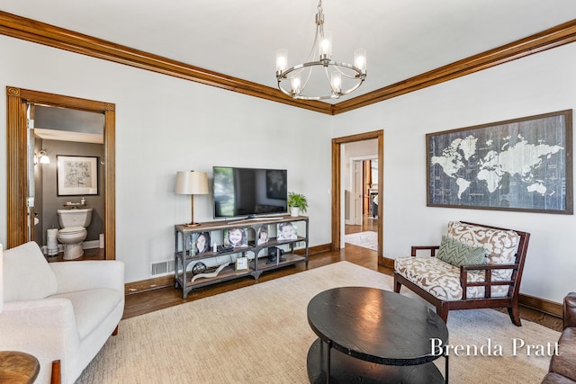living area featuring crown molding, baseboards, a notable chandelier, and wood finished floors
