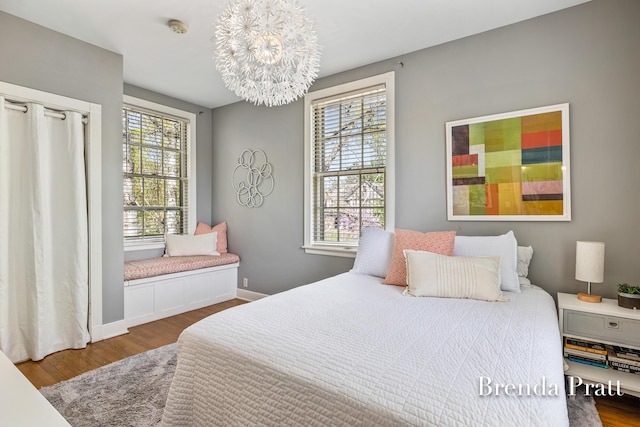 bedroom featuring wood finished floors, a chandelier, and multiple windows