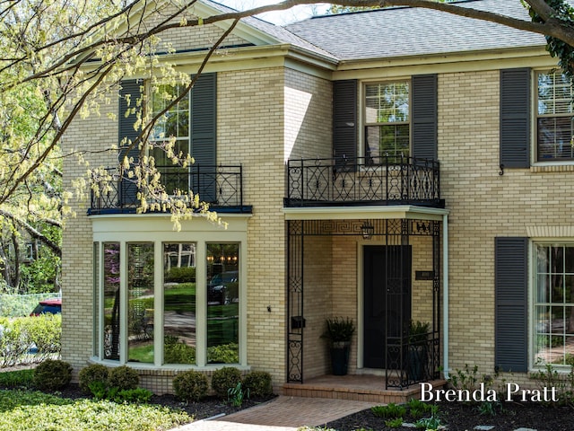 view of front of home with brick siding and a balcony