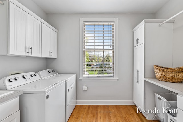 laundry room with cabinet space, a wealth of natural light, washer and clothes dryer, and light wood-style floors