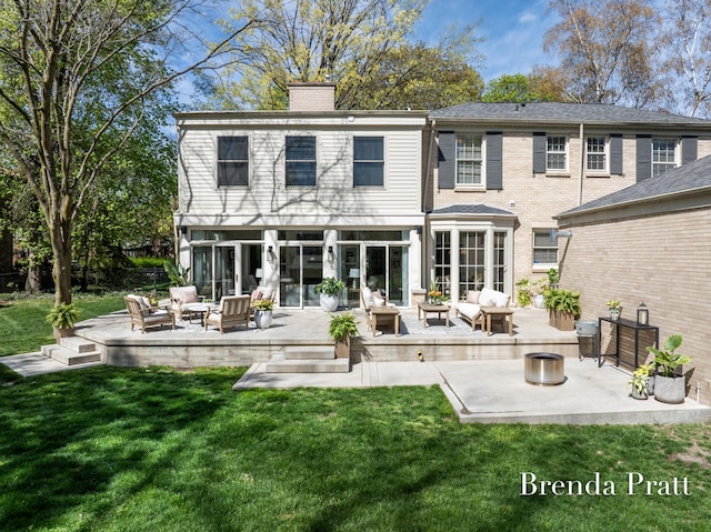 back of property with a chimney, a patio area, a yard, and an outdoor hangout area