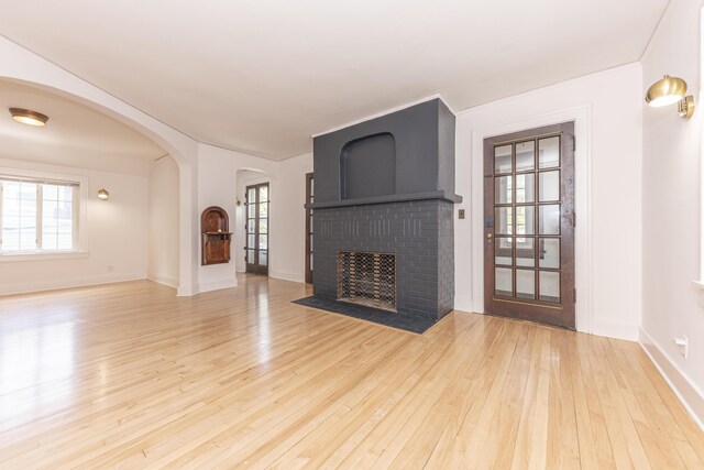 unfurnished living room featuring baseboards, plenty of natural light, a fireplace, and hardwood / wood-style floors