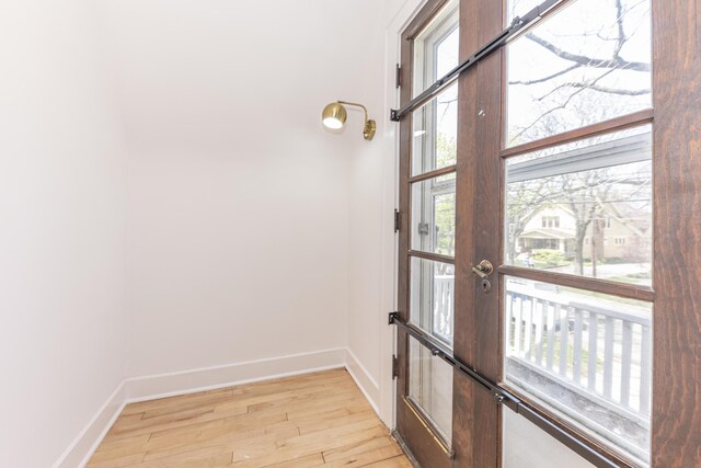 doorway with baseboards and light wood-style flooring