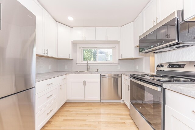 kitchen featuring a sink, light wood-style flooring, appliances with stainless steel finishes, and white cabinets