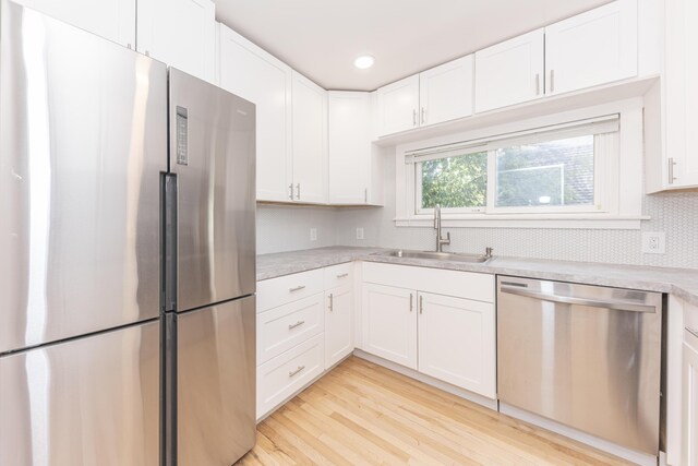 kitchen featuring a sink, light countertops, white cabinets, light wood-style floors, and stainless steel appliances