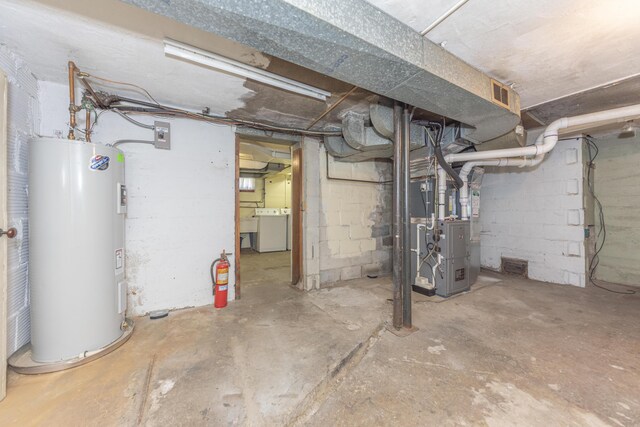 unfinished basement with visible vents, heating unit, water heater, and washer / dryer