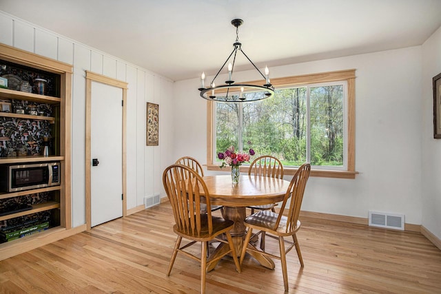 dining space featuring baseboards, light wood-style flooring, a chandelier, and visible vents