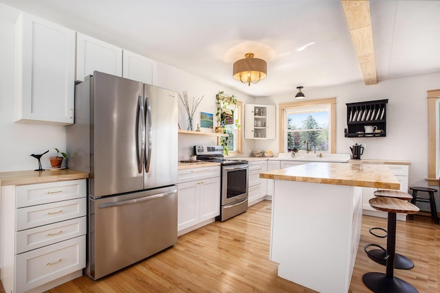 kitchen with butcher block countertops, a breakfast bar area, white cabinetry, light wood finished floors, and appliances with stainless steel finishes