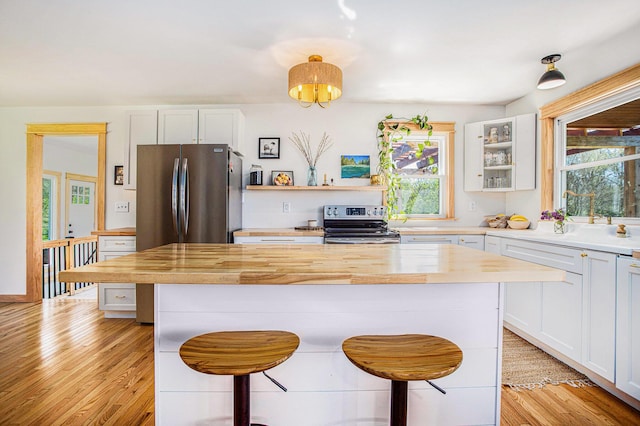 kitchen featuring stainless steel appliances, a breakfast bar, wooden counters, and a wealth of natural light