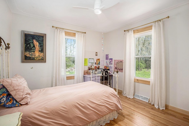 bedroom with light wood-style floors, baseboards, multiple windows, and visible vents