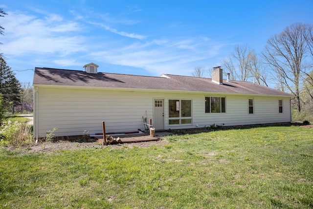 rear view of house featuring a chimney and a yard