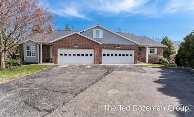 view of front of property with brick siding, a garage, and aphalt driveway