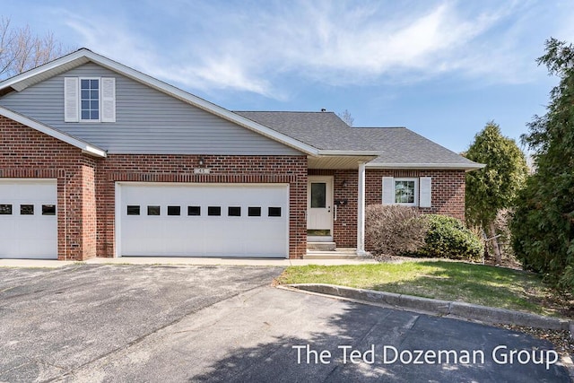 view of front of house featuring a garage, a shingled roof, driveway, and brick siding