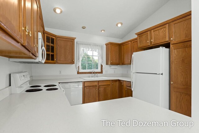 kitchen featuring vaulted ceiling, brown cabinets, a sink, light countertops, and white appliances