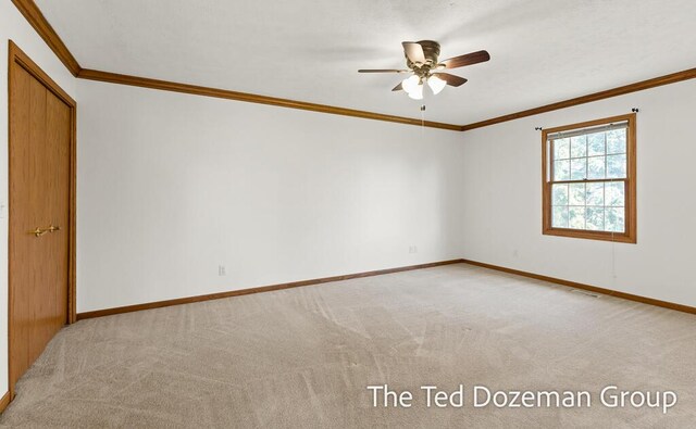 spare room featuring light colored carpet, ornamental molding, and ceiling fan