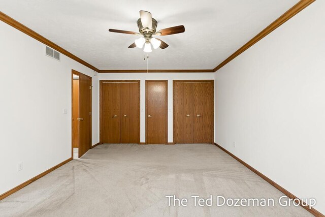 unfurnished bedroom with multiple closets, baseboards, light colored carpet, and visible vents