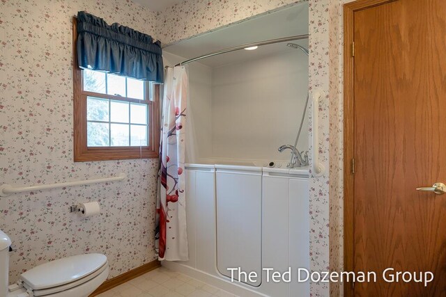 full bath with baseboards, toilet, wallpapered walls, and a shower with shower curtain