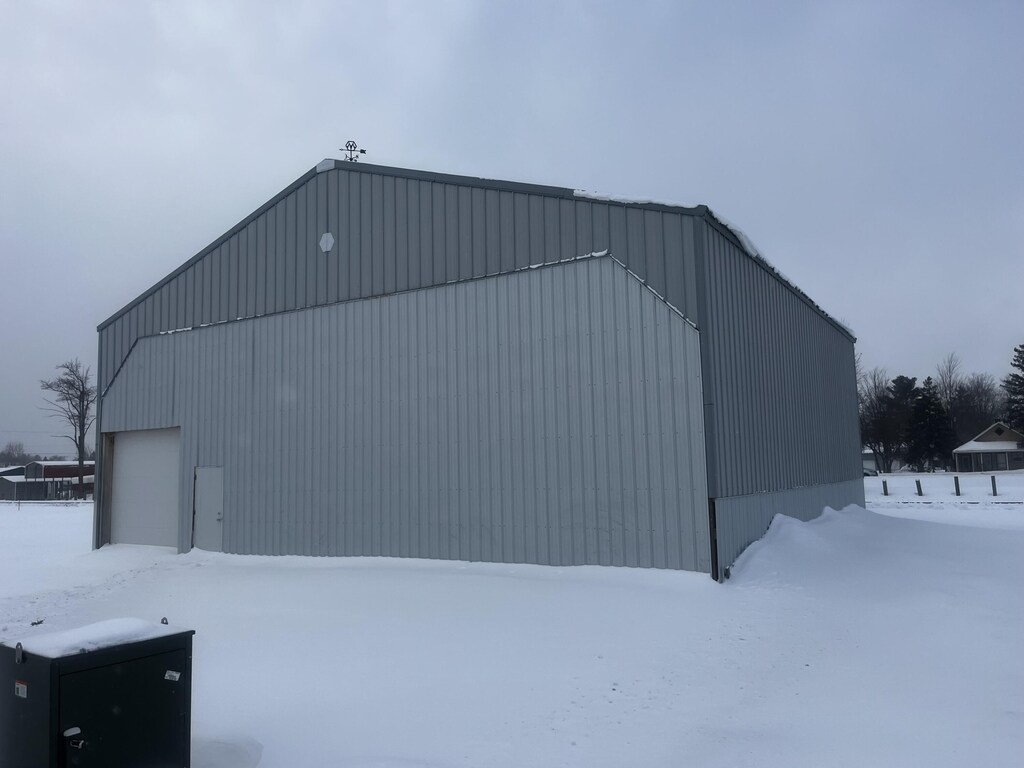 snow covered structure with an outbuilding