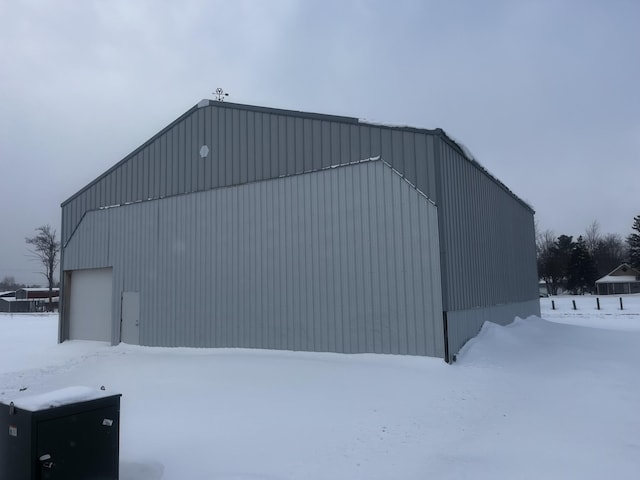 snow covered structure with an outbuilding