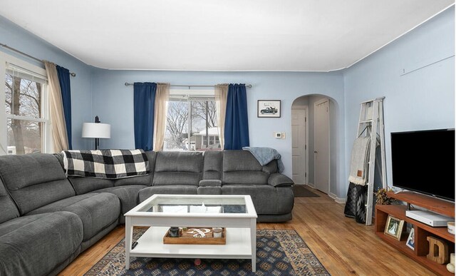 living room with arched walkways and wood finished floors