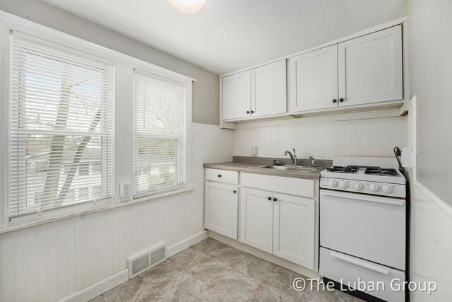 kitchen featuring white cabinetry, a sink, visible vents, and gas range gas stove