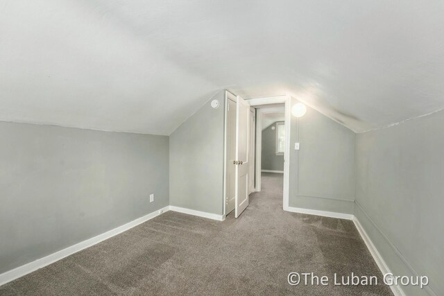 additional living space featuring carpet floors, baseboards, and vaulted ceiling
