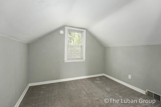 additional living space with visible vents, carpet, baseboards, and lofted ceiling