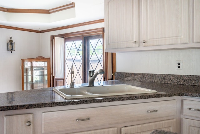kitchen with ornamental molding, dark countertops, white cabinetry, a tray ceiling, and a sink