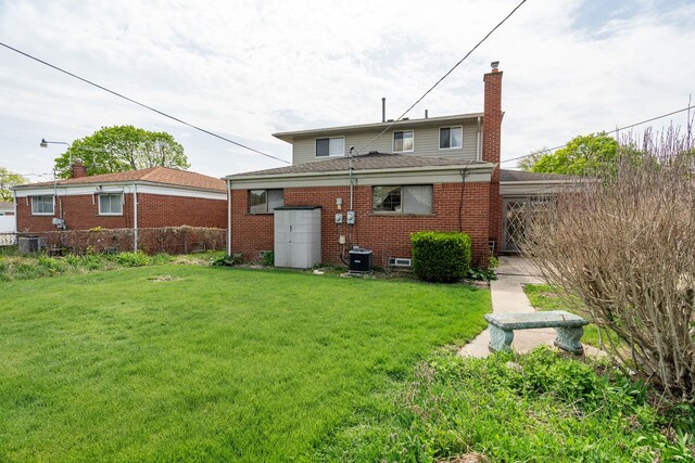 rear view of property with fence, a chimney, a yard, and brick siding