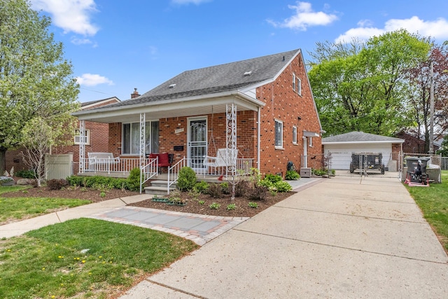 bungalow-style house featuring covered porch, a front yard, brick siding, an outbuilding, and a detached garage