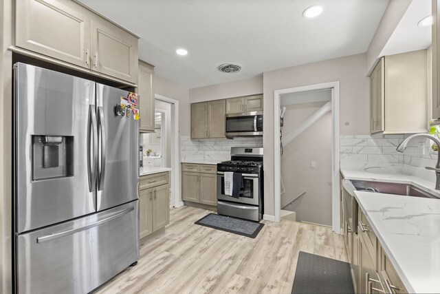 kitchen with light stone counters, light wood-style flooring, stainless steel appliances, recessed lighting, and decorative backsplash