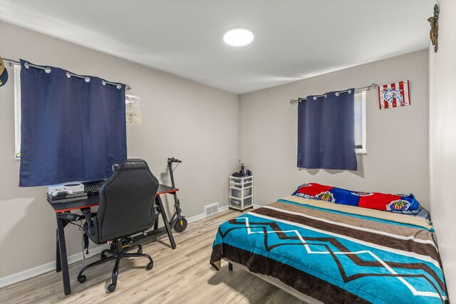 bedroom with visible vents, baseboards, and wood finished floors