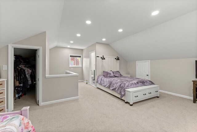 bedroom with a walk in closet, baseboards, light carpet, and lofted ceiling