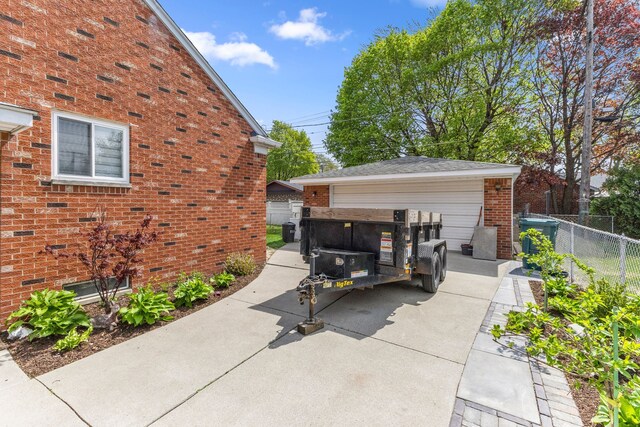 view of side of property with a detached garage, brick siding, and fence