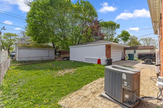 view of yard featuring an outdoor structure, a garage, central AC, and fence