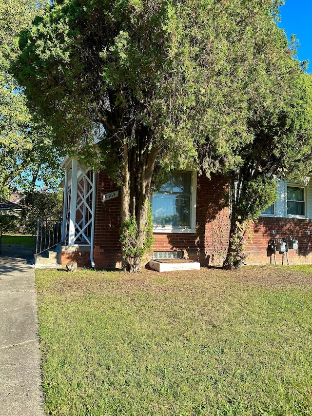 obstructed view of property featuring a front lawn and brick siding