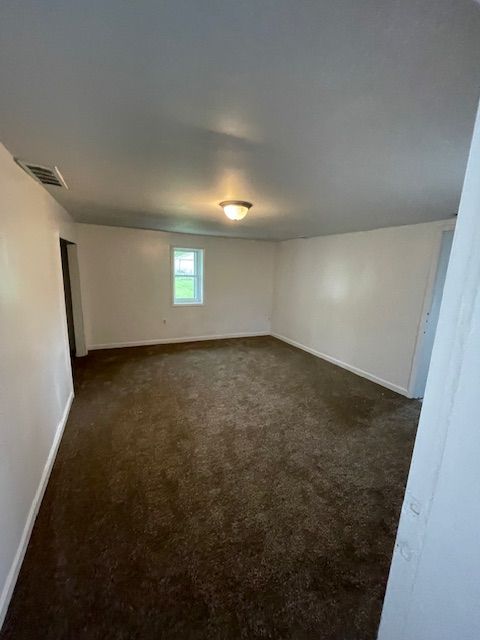 basement with baseboards and dark colored carpet